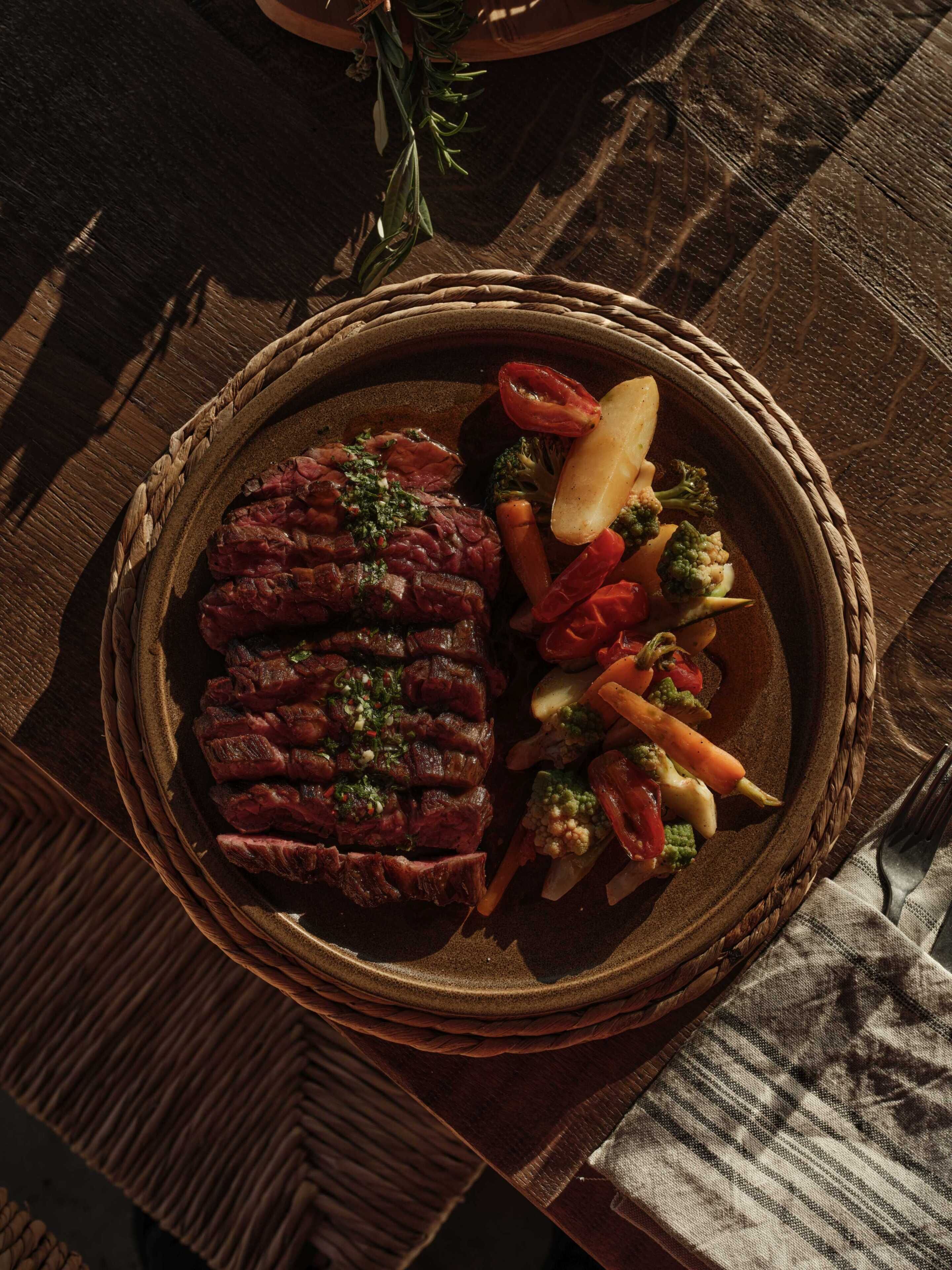 A woven basket containing sliced meat, vegetables, and a sprig of rosemary.