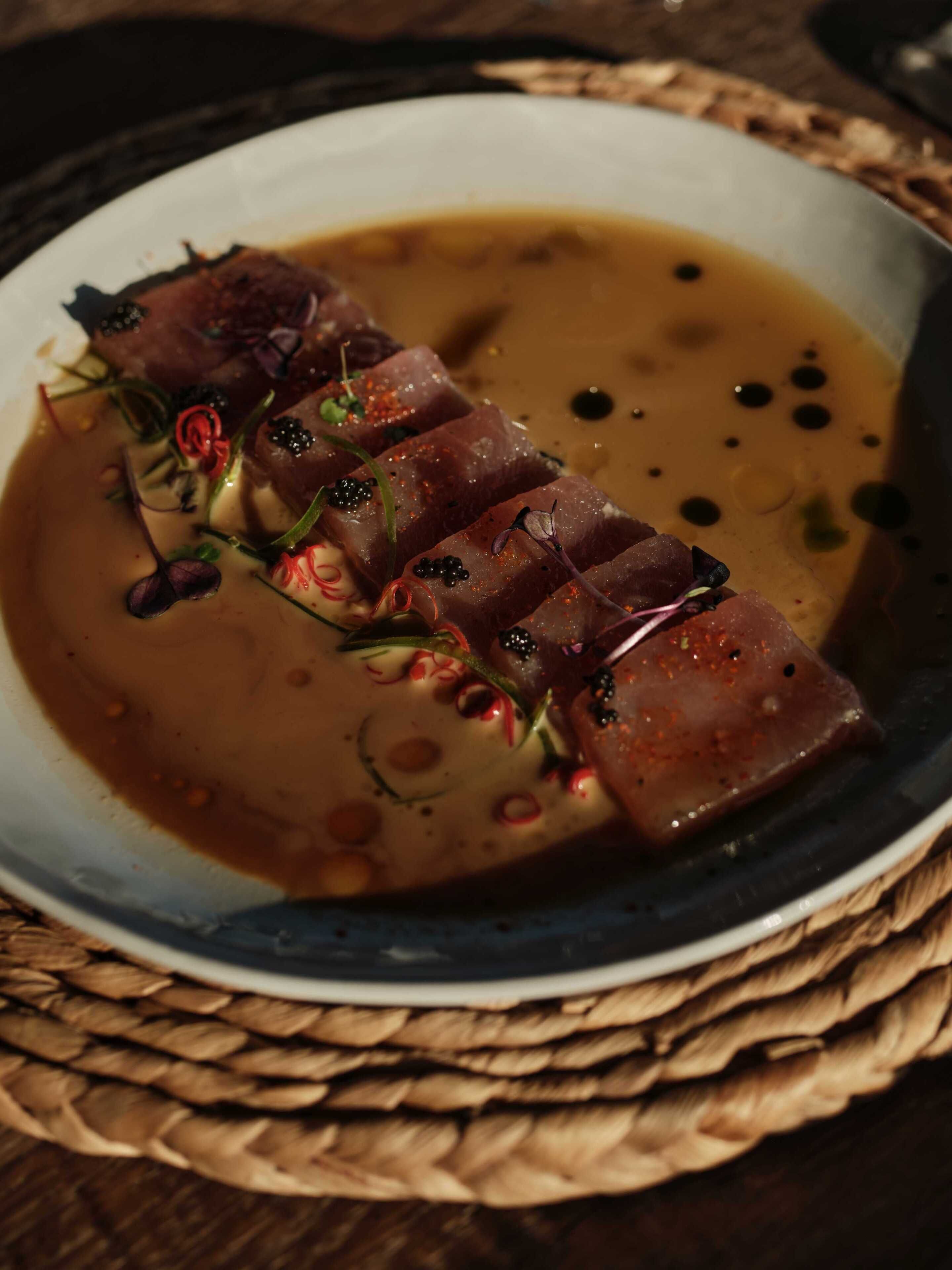 Un plato con carne en rodajas y salsa.