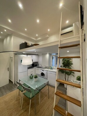 A compact kitchen with a dining area, a washing machine, and a small table with chairs.