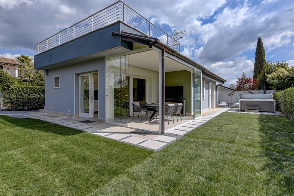 A modern house with a covered patio, large windows, and a well-maintained lawn.
