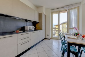 A kitchen with white cabinets, a microwave, and a dining area with a table set for two.