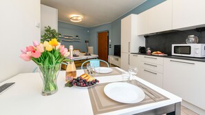 Eine moderne Küche mit weißen Schränken, einer Mikrowelle und einem Essbereich mit gedecktem Tisch für zwei Personen.