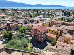 A town with terracotta-roofed buildings, a central square, and a view of the sea.