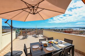 A rooftop terrace with a table set for dining, chairs, and a large umbrella. - Palazzo Garda  - Lakeview Penthouse 4 (Toscolano-Maderno)