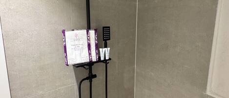 A shower with a black rain showerhead, a handheld showerhead, and a handheld massager.