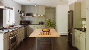 A modern kitchen with stainless steel appliances, a wooden island, and a view of the adjacent dining area.