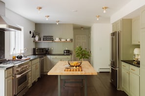 A modern kitchen with stainless steel appliances, a wooden island, and a view of the adjacent dining area.