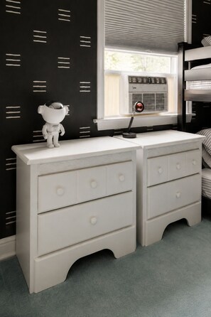 A bedroom with a white dresser, a bunk bed, and a window with blinds. - Hot Tub, Fire Pit, Theater, Games & EV | Sleeps 8 (Barryville)