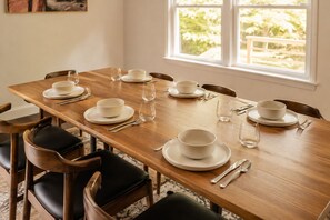 A dining table set with white plates, bowls, and cutlery, with chairs around it. - Hot Tub, Fire Pit, Theater, Games & EV | Sleeps 8 (Barryville)