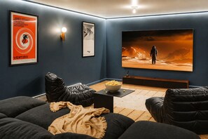 Una sala de cine en casa con una pantalla grande, asientos cómodos y un cuenco de palomitas de maíz.