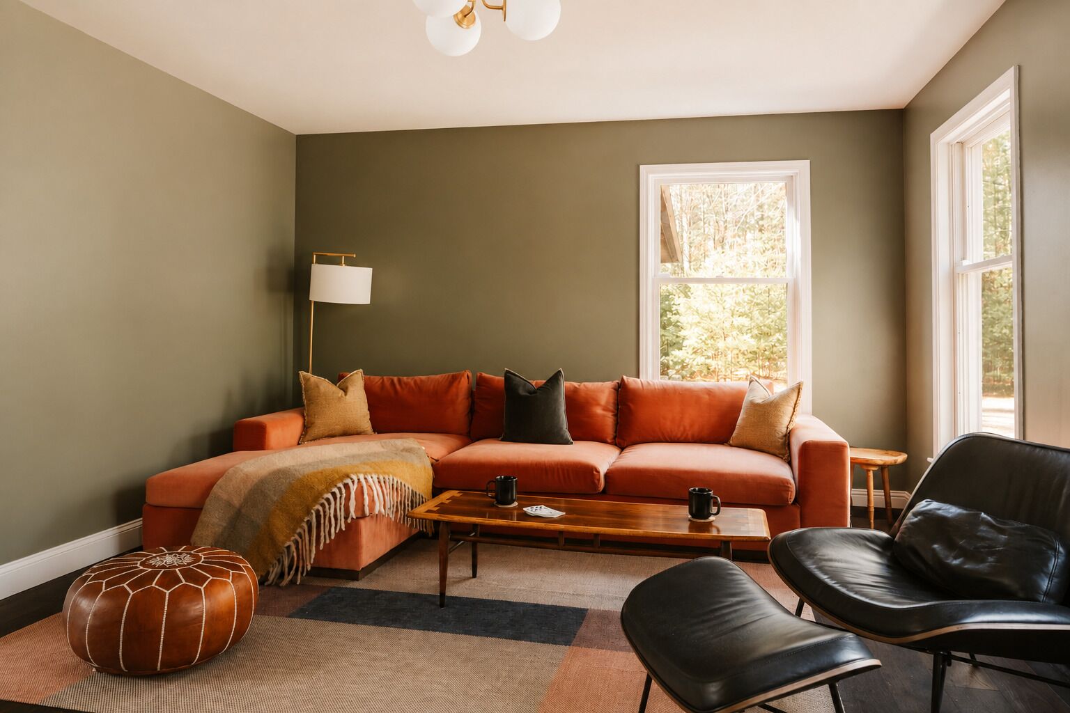A living room with a sofa, coffee table, ottoman, and a chair.