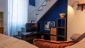 A modern living room with a flat-screen TV, a staircase, and a blue accent wall.