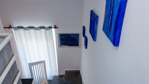 A staircase with a white wall, a framed picture of a cat, and blue curtains.