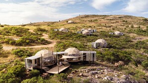 A series of dome-shaped accommodations in a natural landscape with a dirt path leading to a wooden deck. - Piedra de las Animas (Nueva Carrara)