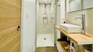 Une salle de bain moderne avec une douche à parois de verre, un lavabo blanc et un meuble-lavabo en bois.