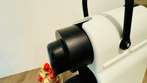 Un appareil de chauffage portatif noir et blanc, doté d’une poignée, posé sur une surface en bois.