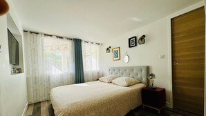 Une chambre à coucher avec un lit, une table de chevet, un miroir et une porte en bois.