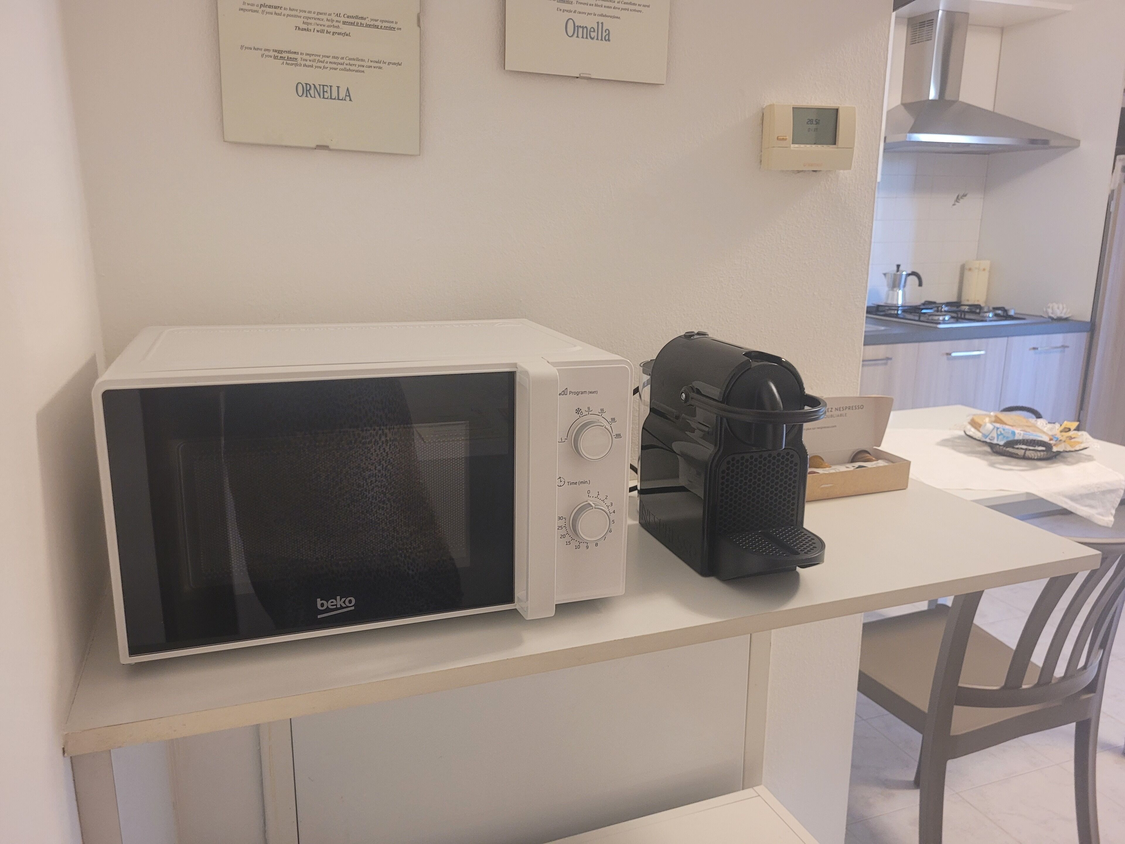 A kitchenette with a microwave, coffee machine, and a small table.