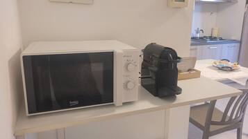 A kitchenette with a microwave, coffee machine, and a small table.