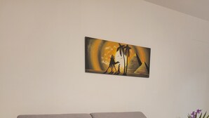 Un sofá gris en una habitación con un cuadro en la pared y una mesita con un florero.