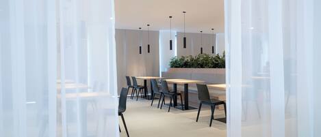 A modern meeting room with glass partitions, black chairs, and a central table with a plant.