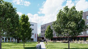 Een modern gebouwcomplex met een centrale looppad, omgeven door bomen en gras.