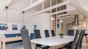 A modern dining area with a round table, black chairs, and pendant lighting. - 5 Star Holiday Home in Lokken (Lokken)