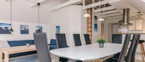 A modern dining area with a round table, black chairs, and pendant lighting.