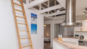 A modern kitchen with a stainless steel range hood, wooden counter, and a loft bedroom with a view of the sky. - 5 Star Holiday Home in Lokken (Lokken)