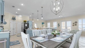 A spacious dining area with a wooden table set for six, surrounded by white chairs. - Makin' Memories 4 BR 4.5 Bath Home w/Private Pool, Elevator and Hot Tub (St. George Island)