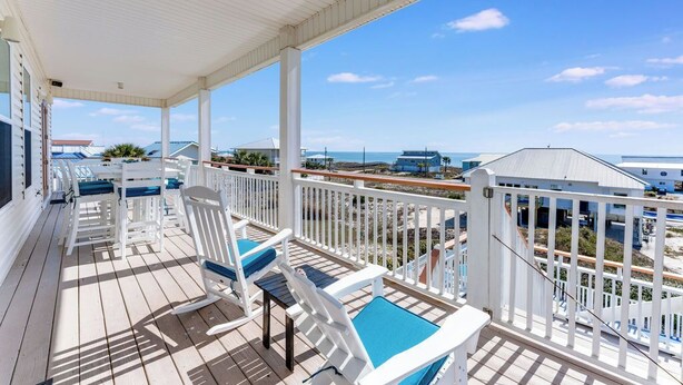 A covered outdoor area with white railings and blue cushions on white chairs. - Makin' Memories 4 BR 4.5 Bath Home w/Private Pool, Elevator and Hot Tub (St. George Island)