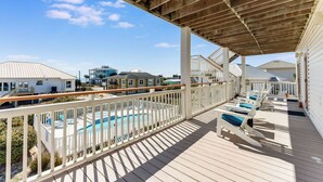 A wooden deck with a pool and lounge chairs, overlooking a residential area. - Makin' Memories 4 BR 4.5 Bath Home w/Private Pool, Elevator and Hot Tub (St. George Island)