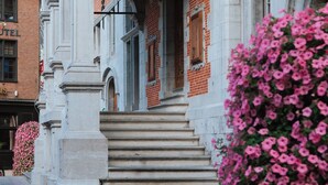 A building with a brick facade, a large arched entrance, and steps leading up to it. - La Petite Foret | Contemporary Apartment in the Peaceful Brussels Periphery (Halle)