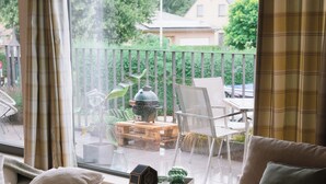 A living room with two sofas, a coffee table with candles, and a view of a balcony with outdoor furniture. - La Petite Foret | Contemporary Apartment in the Peaceful Brussels Periphery (Halle)