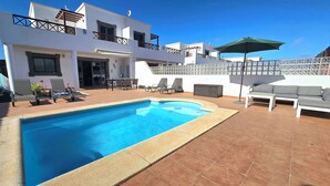 A modern two-story house with a swimming pool, outdoor seating, and a tiled patio. - Villa Zinnia - heated pool, aircon, large terrace with sun and shade all day (playa blanca)