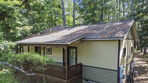 Une petite cabane à un seul étage, dotée d’un toit en pente, d’un porche et d’une cour clôturée.