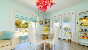 A dining area with a round table, white chairs, and a chandelier.
