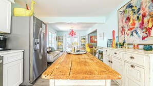 A spacious kitchen with a wooden table, white cabinets, and a stainless steel refrigerator.