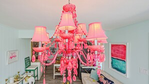 A room with a chandelier, a sofa, a dining table, and a chair.