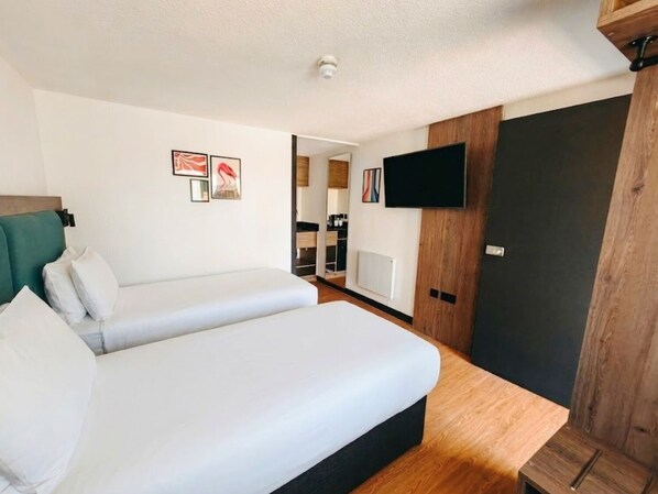 A hotel room with a bed, a TV, and a wooden wardrobe.