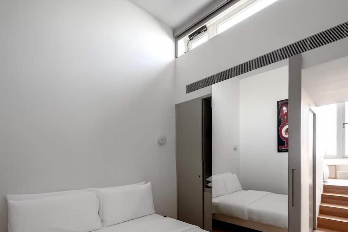 A modern bedroom with a large bed, a wardrobe, and a mirror reflecting the room.