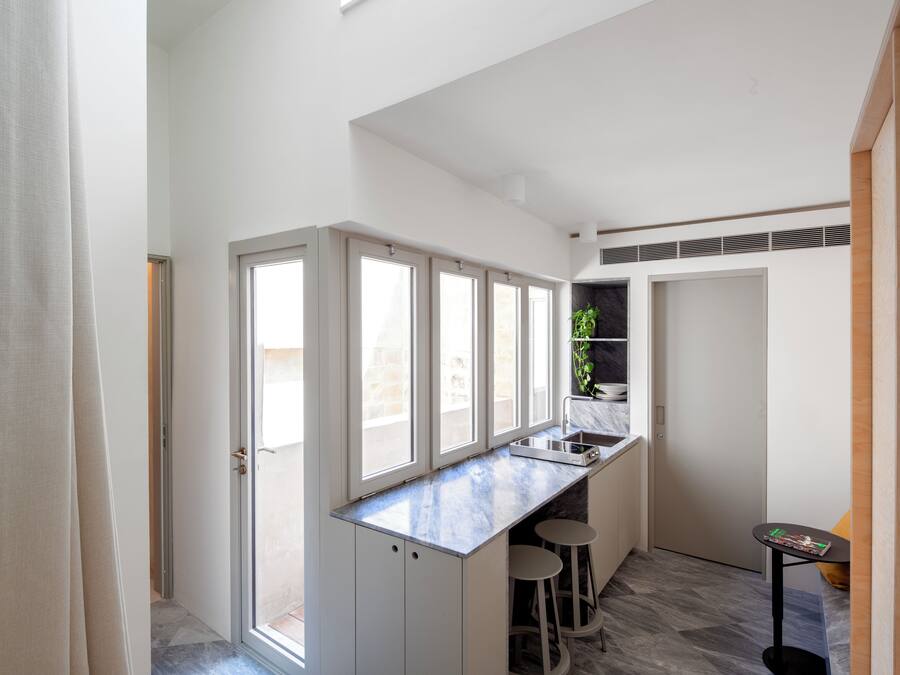 A modern kitchen with a marble countertop, a built-in stove, and a small bar area with stools.