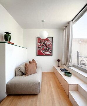 A modern, minimalist living space with a sofa, a small table, and a large window. - Stilla, 6, Triq San Lazzru (Cospicua)