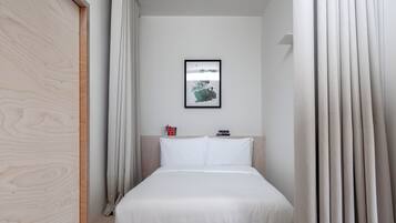 A bedroom with a bed, a framed picture on the wall, and a wooden wardrobe.