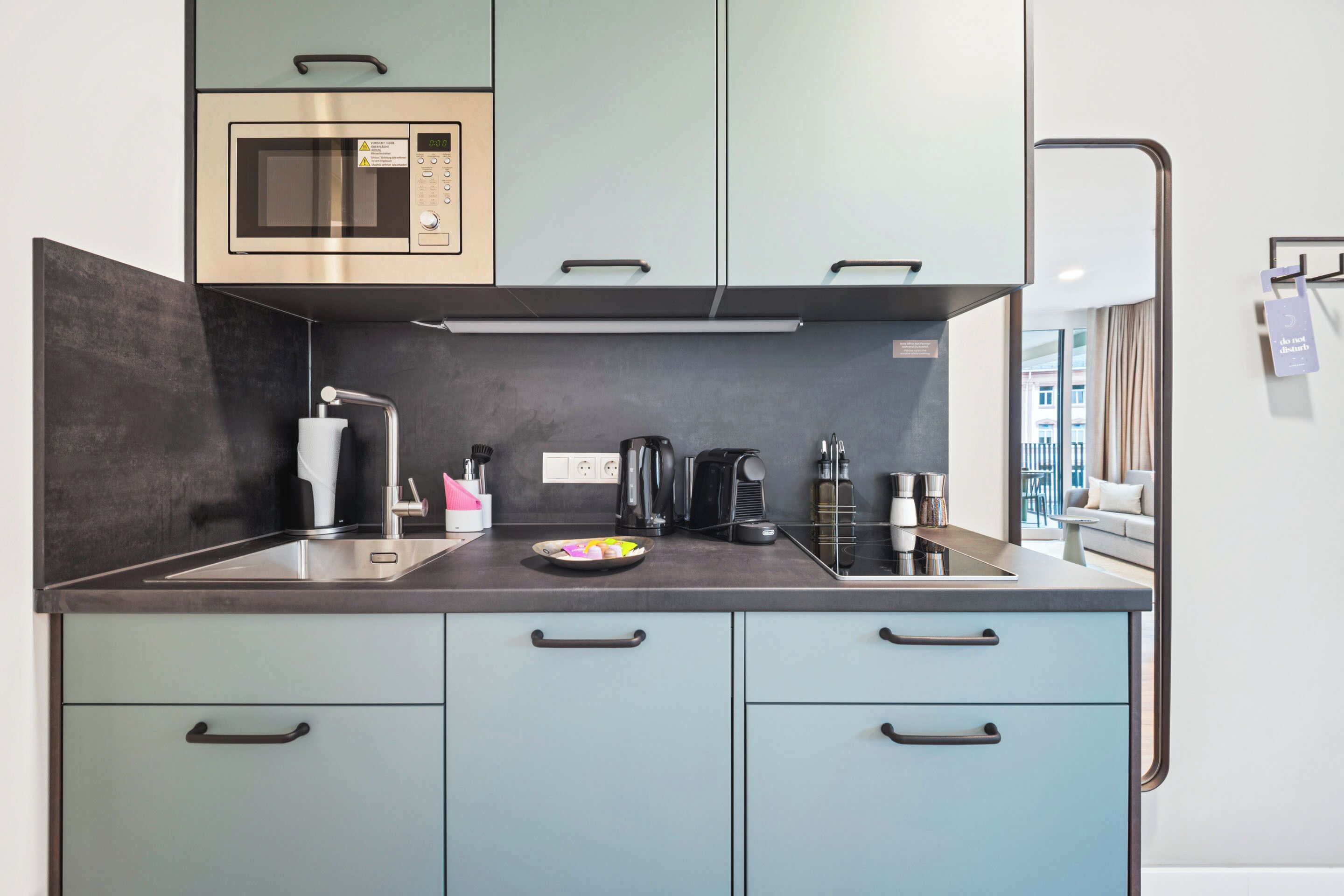 A modern kitchen with a microwave, coffee maker, and kettle on the counter.