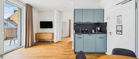 Un apartamento moderno con cocina, comedor y un amplio ventanal corredizo al exterior.