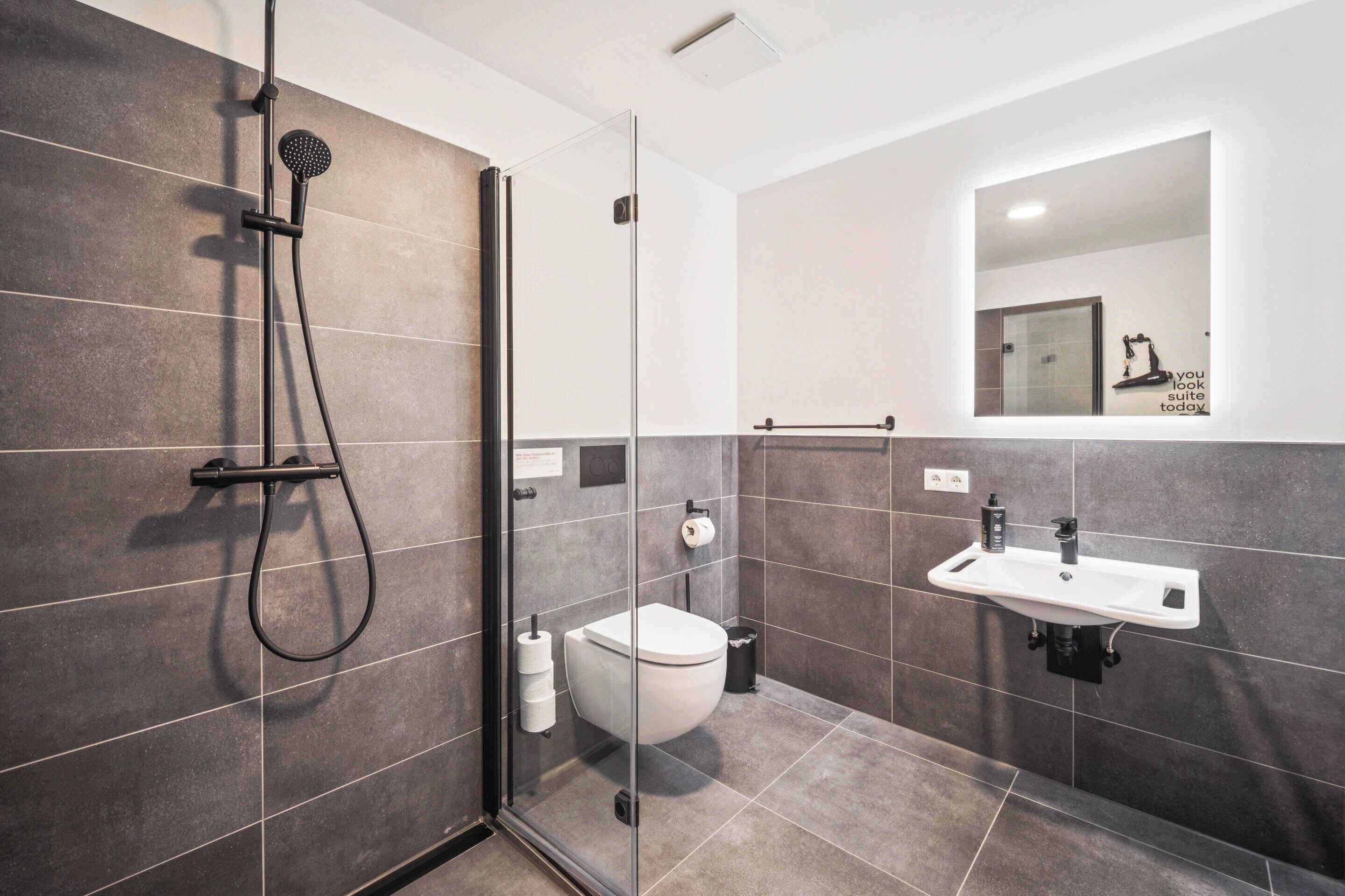 A modern bathroom with a glass-enclosed shower, a white sink, and a toilet.
