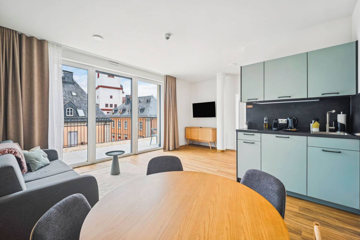 Un apartamento moderno con comedor, cocina y grandes puertas de cristal correderas a un balcón.