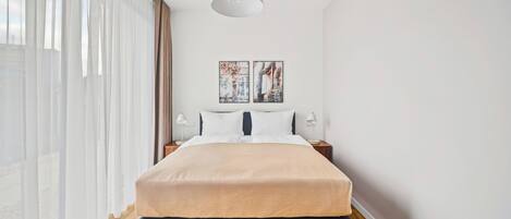 A modern bedroom with a bed, bedside tables, and artwork on the wall.