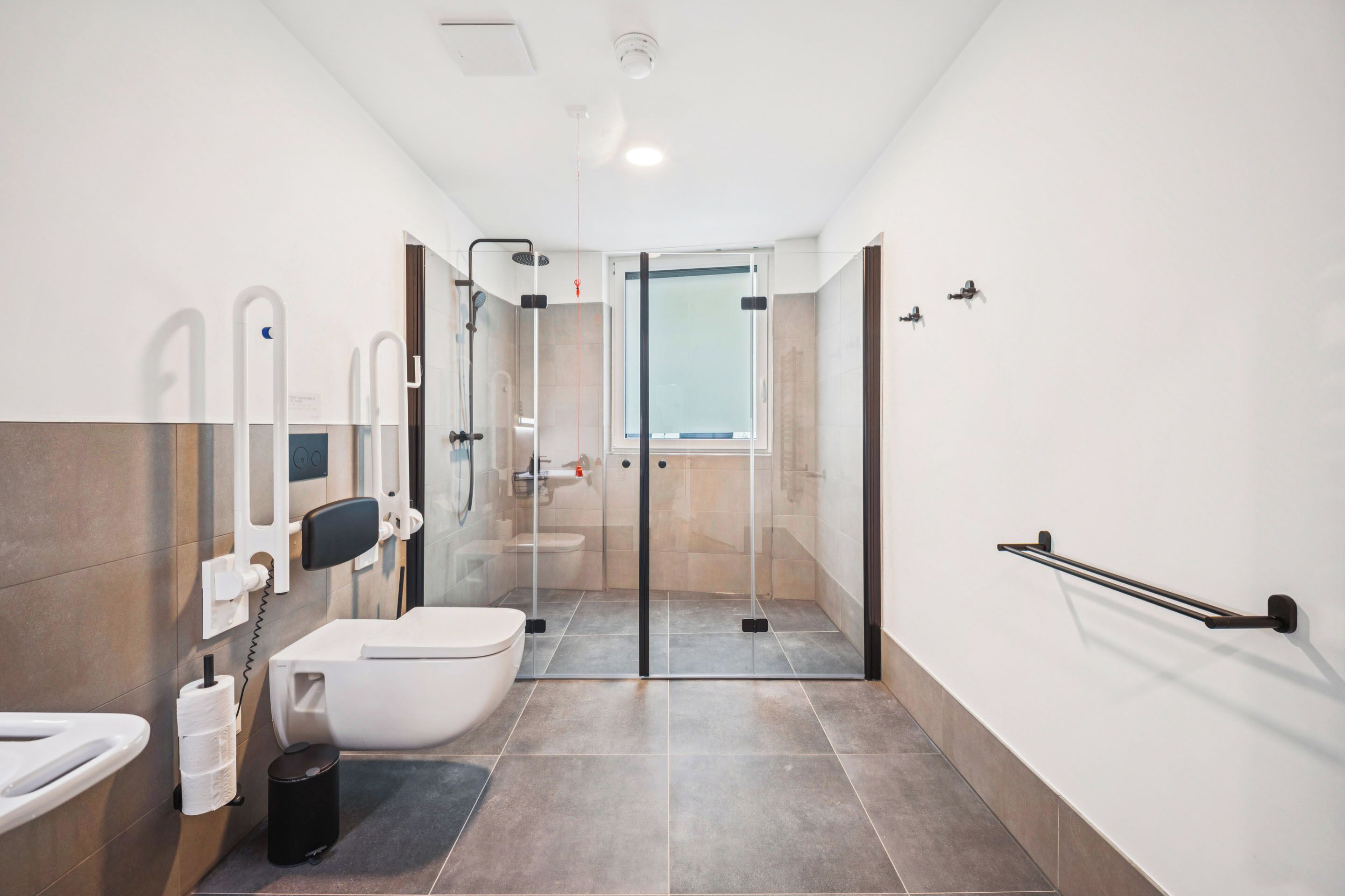 A modern bathroom with a toilet, bidet, and glass shower enclosure.